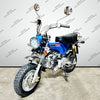 A blue and silver mini dirt bike motorcycle with a black seat, front round headlight, and knobby tires, photographed indoors against a light gray wall with repeating VENOM MOTORSPORTS watermarks.